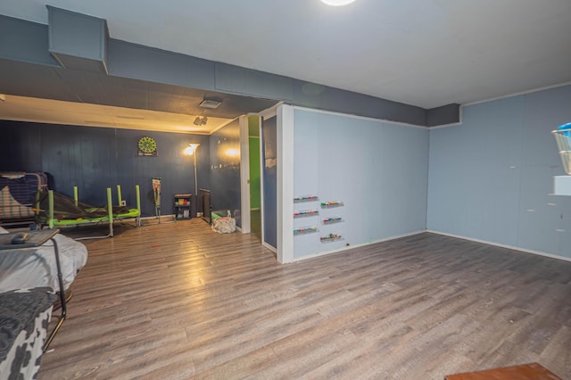 finished below grade area featuring baseboards, wood walls, and wood finished floors