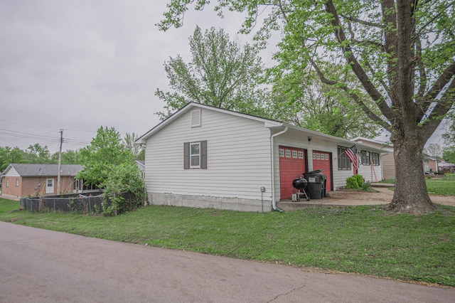 view of property exterior featuring an attached garage, a lawn, fence, and driveway