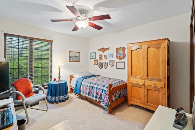 bedroom with ceiling fan, light carpet, and a textured ceiling