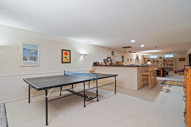 recreation room with ceiling fan, a textured ceiling, and light colored carpet