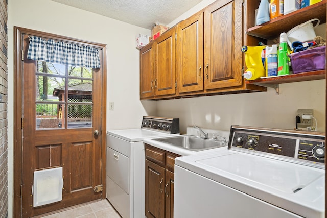 clothes washing area with a textured ceiling, cabinet space, light tile patterned floors, a sink, and separate washer and dryer