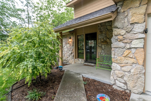 doorway to property featuring roof with shingles and stone siding