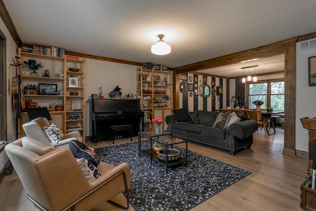 living room featuring crown molding, visible vents, wood finished floors, and a notable chandelier
