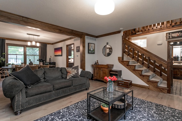 living room with crown molding, wood finished floors, stairway, and beamed ceiling