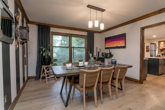 dining area featuring crown molding, baseboards, and light wood-type flooring