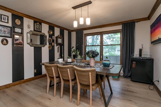 dining space featuring baseboards, ornamental molding, and light wood-style flooring