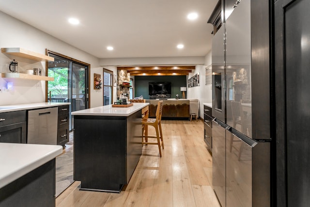 kitchen with appliances with stainless steel finishes, light countertops, a kitchen breakfast bar, a center island, and light wood-type flooring