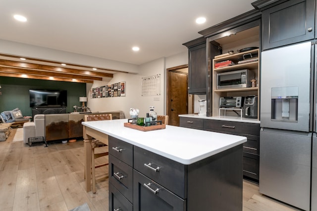 kitchen with appliances with stainless steel finishes, a center island, light countertops, open floor plan, and light wood-style floors