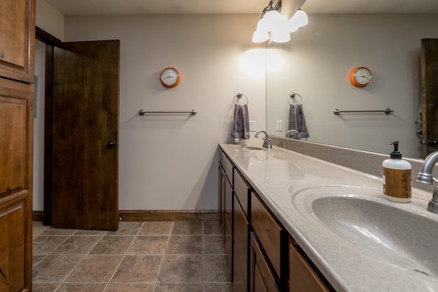 bathroom with double vanity, baseboards, and a sink