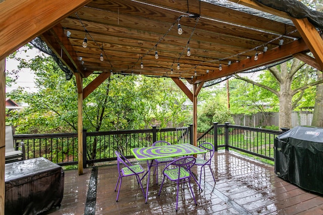 wooden terrace with grilling area, fence, and outdoor dining space