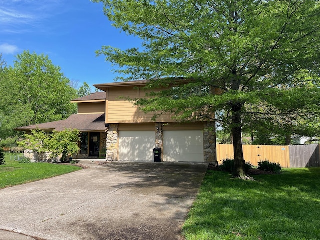 view of front of property with concrete driveway, a front yard, fence, and stone siding