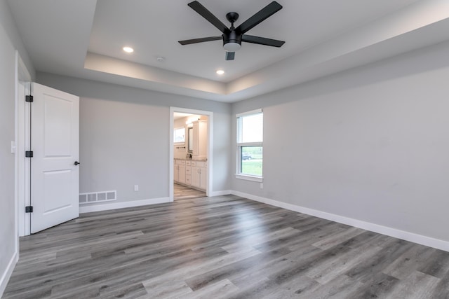 15070 Ada Dr, Hallsville, MO 65255 - unfurnished bedroom featuring recessed lighting, baseboards, wood finished floors, a tray ceiling, and visible vents