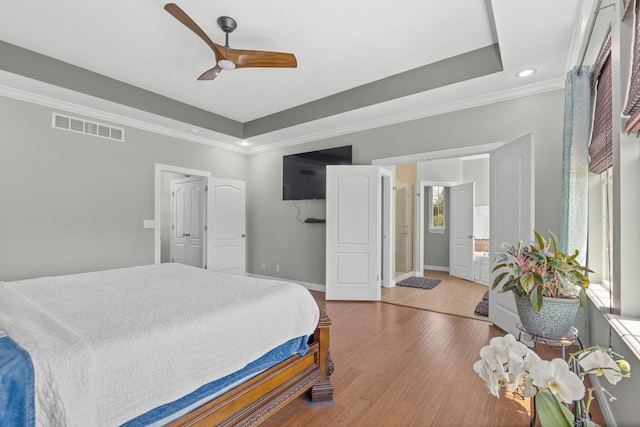bedroom featuring a tray ceiling, visible vents, ornamental molding, and baseboards