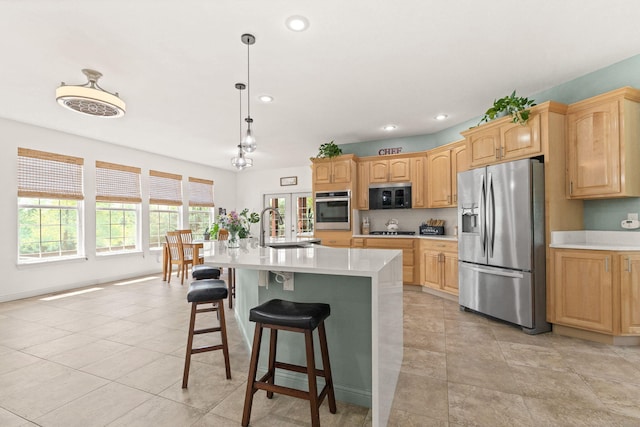 kitchen with appliances with stainless steel finishes, a sink, light countertops, a breakfast bar, and recessed lighting