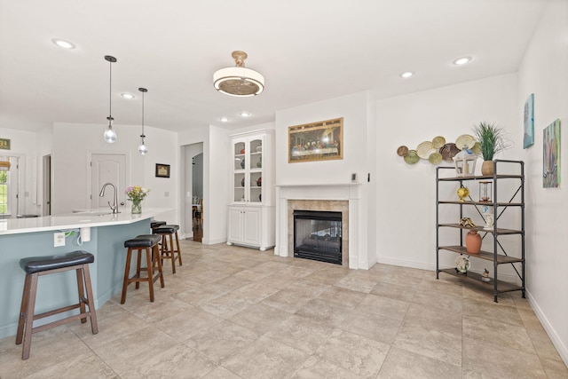 kitchen with light countertops, recessed lighting, a glass covered fireplace, and a kitchen bar