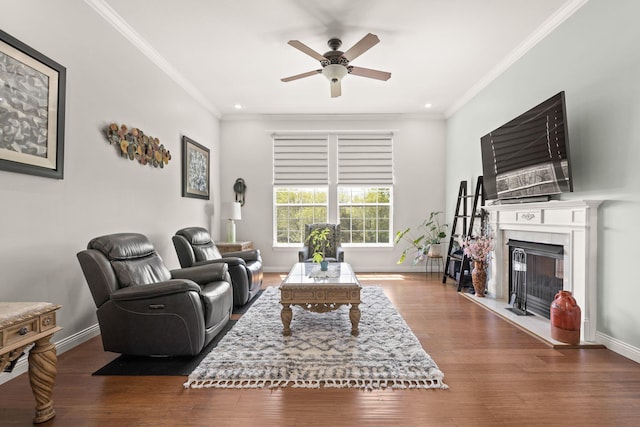 living room with a ceiling fan, baseboards, ornamental molding, and a tile fireplace