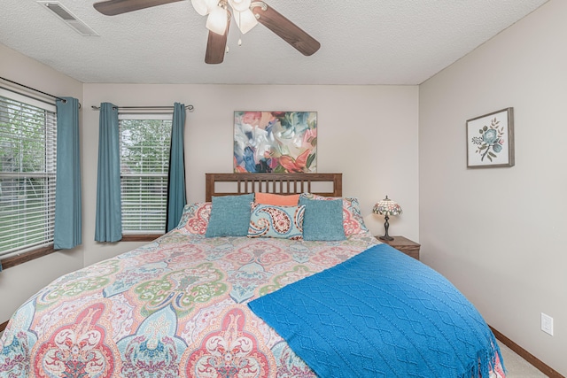 carpeted bedroom featuring visible vents, a ceiling fan, and a textured ceiling