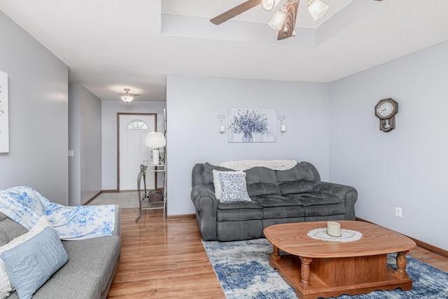 living room with light wood-style floors, baseboards, and a ceiling fan