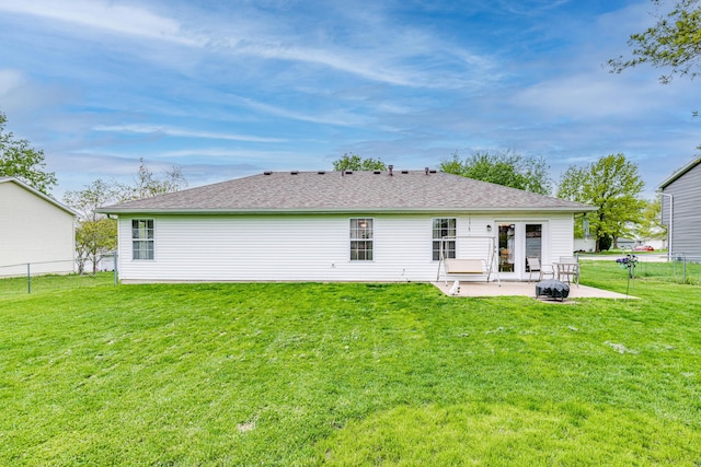 back of property with a lawn, fence, a shingled roof, and a patio area