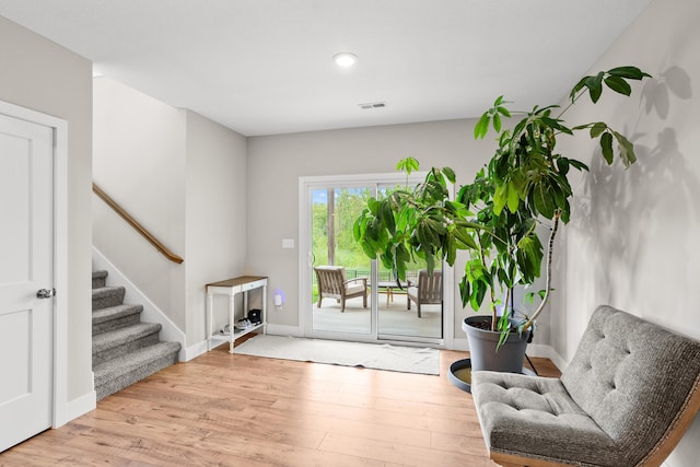 interior space with stairway, baseboards, wood finished floors, and visible vents