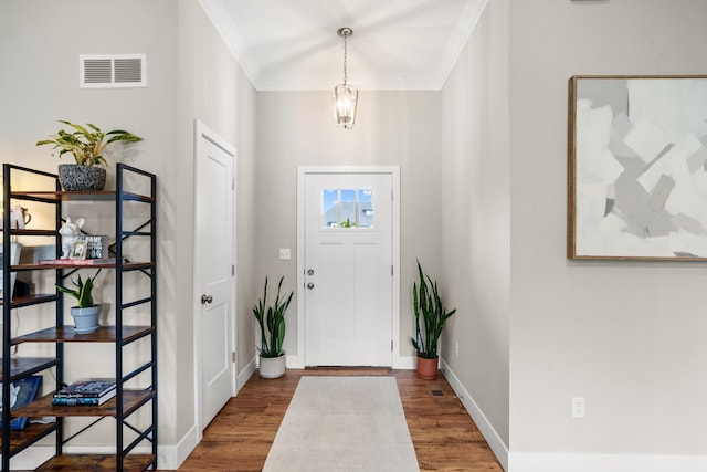 foyer entrance with baseboards, ornamental molding, wood finished floors, and visible vents