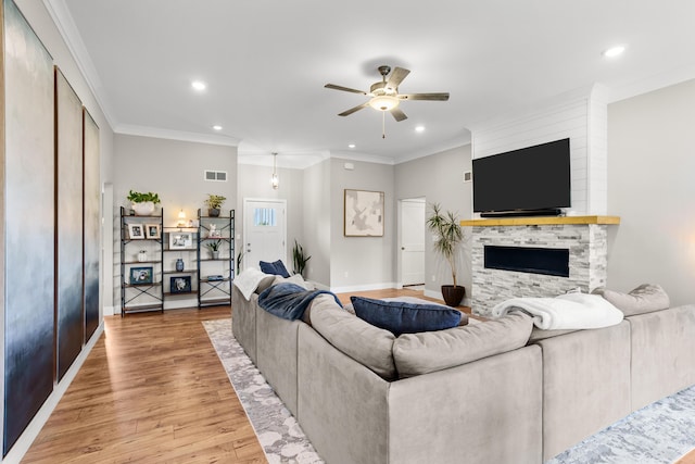 living room with light wood finished floors, a stone fireplace, a ceiling fan, recessed lighting, and visible vents