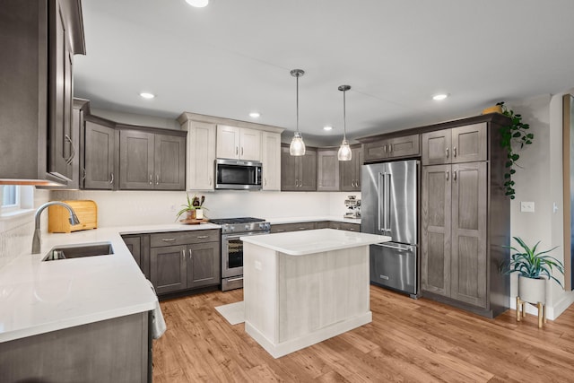 kitchen featuring a sink, light wood finished floors, appliances with stainless steel finishes, and light countertops