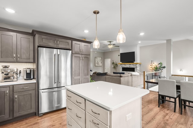 kitchen featuring a fireplace, ceiling fan, a center island, light countertops, and high end refrigerator