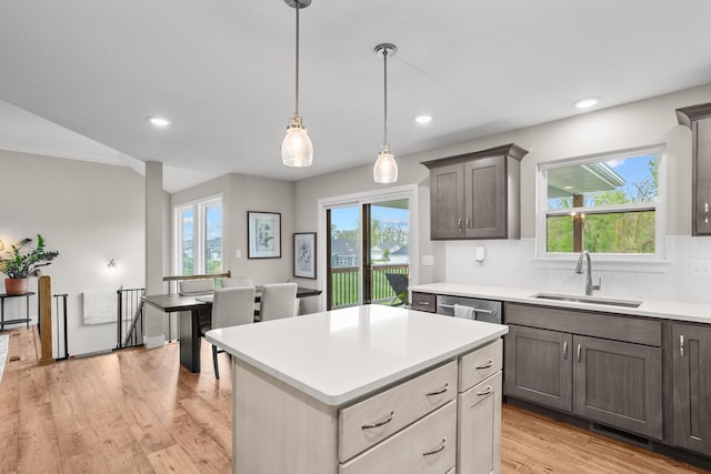 kitchen featuring a sink, light countertops, decorative backsplash, light wood-type flooring, and visible vents