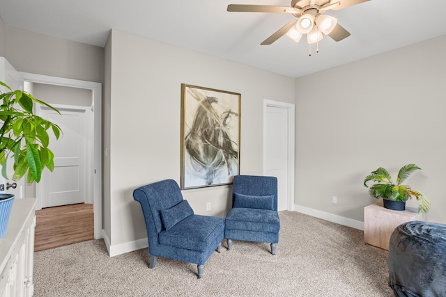 living area with a ceiling fan, baseboards, and light carpet