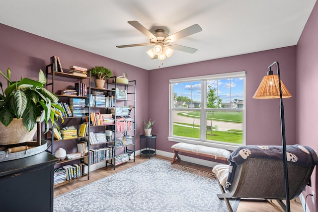 sitting room with baseboards, a ceiling fan, and wood finished floors