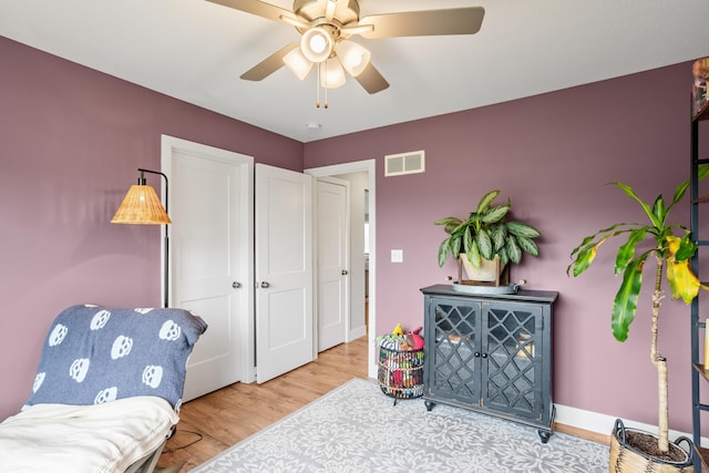 sitting room with visible vents, a ceiling fan, baseboards, and wood finished floors