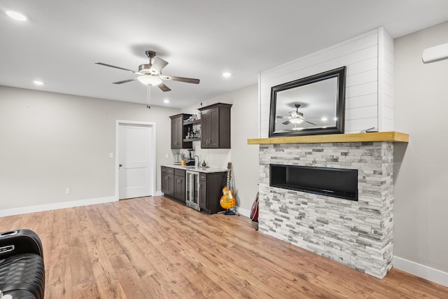unfurnished living room with a ceiling fan, wet bar, a sink, baseboards, and light wood-style flooring