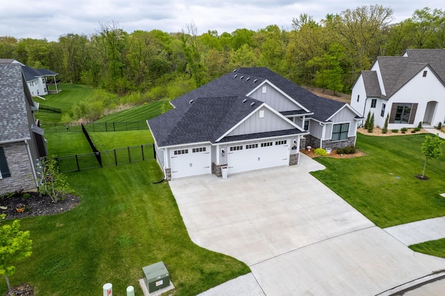 view of front of property featuring board and batten siding, driveway, a front yard, a garage, and fence