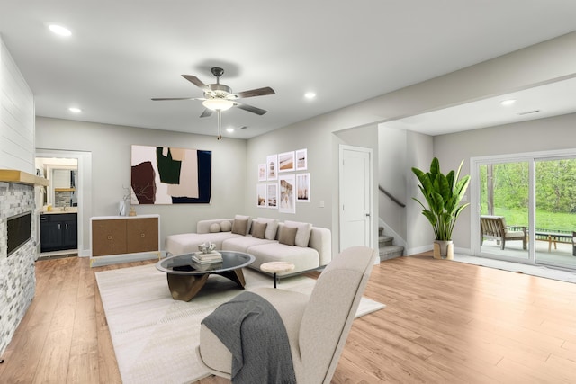 living room with a fireplace, a ceiling fan, recessed lighting, light wood-type flooring, and stairway
