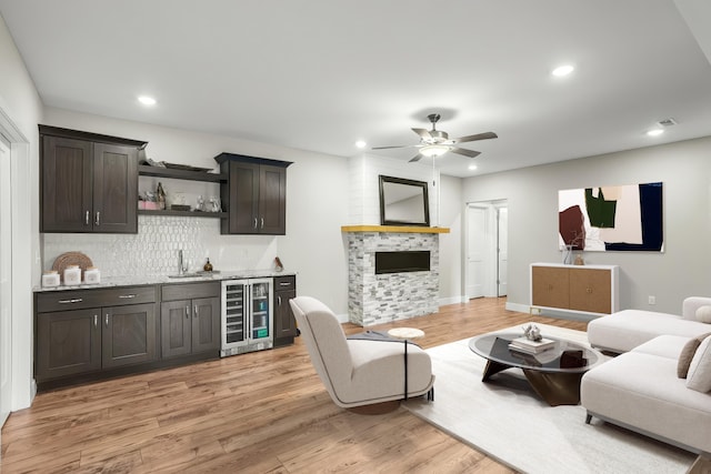 living room featuring light wood finished floors, recessed lighting, wet bar, a ceiling fan, and wine cooler