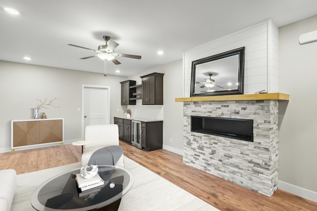 living room with baseboards, ceiling fan, wet bar, and light wood finished floors