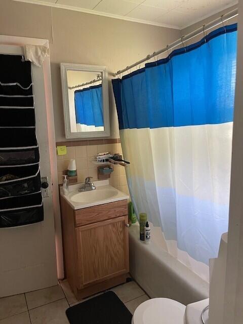 full bathroom with tile patterned flooring, vanity, toilet, tile walls, and shower / bathtub combination with curtain