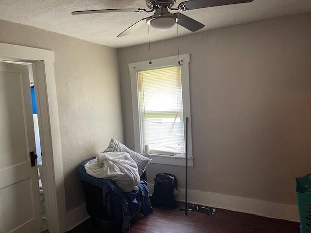 miscellaneous room with baseboards, ceiling fan, and dark wood-style flooring