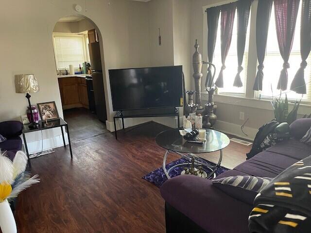 living area featuring baseboards, arched walkways, and wood finished floors
