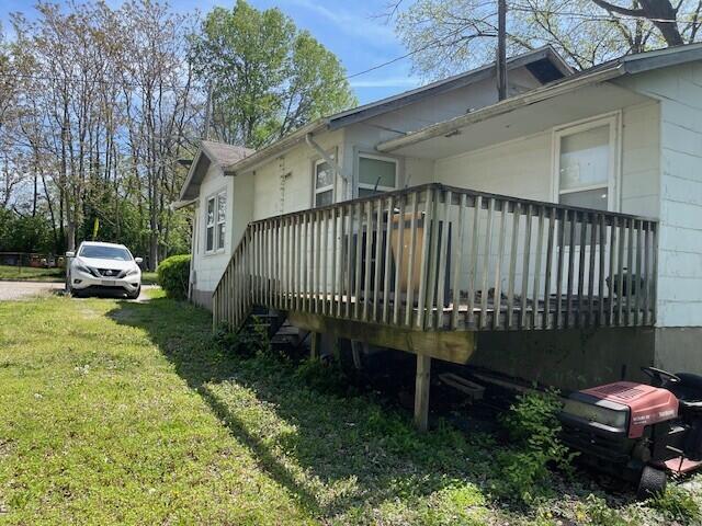 view of side of home featuring a wooden deck and a yard