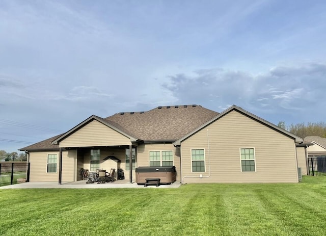 back of property with fence, a patio, roof with shingles, a hot tub, and a yard