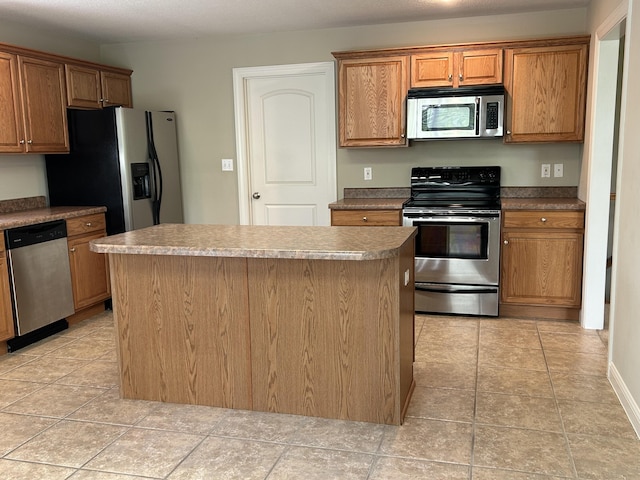 4405 Ferndale Dr, Columbia, MO 65202 - kitchen with brown cabinetry, appliances with stainless steel finishes, light tile patterned floors, and a kitchen island