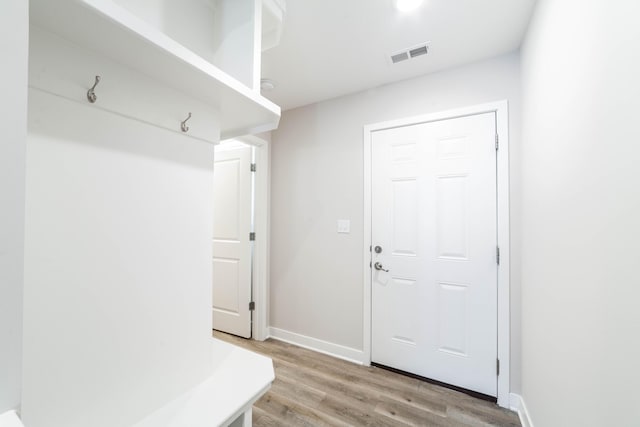mudroom featuring light wood finished floors, baseboards, and visible vents