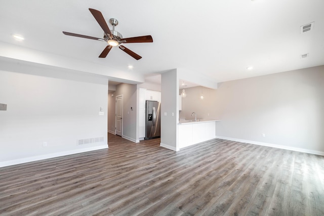unfurnished living room featuring baseboards, visible vents, a sink, and wood finished floors