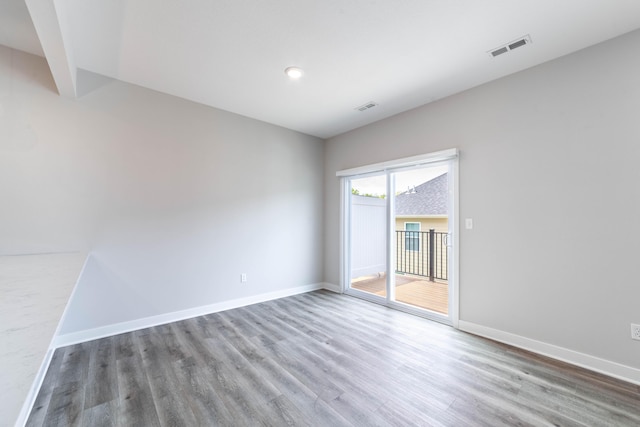 empty room with visible vents, wood finished floors, and baseboards