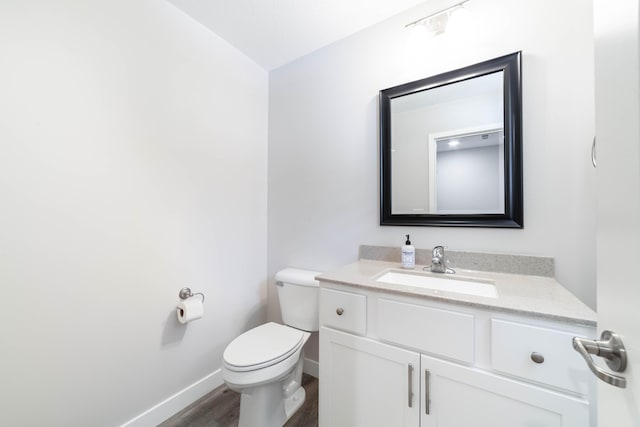bathroom featuring toilet, baseboards, vanity, and wood finished floors