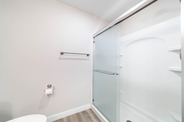full bathroom featuring a shower stall, toilet, and wood finished floors