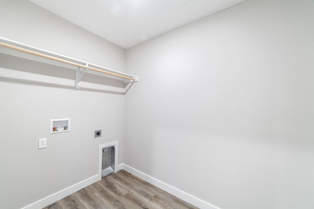 clothes washing area with baseboards, washer hookup, wood finished floors, hookup for an electric dryer, and laundry area