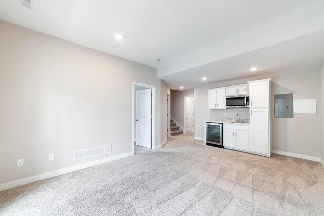 kitchen featuring wine cooler, visible vents, stainless steel microwave, electric panel, and light carpet